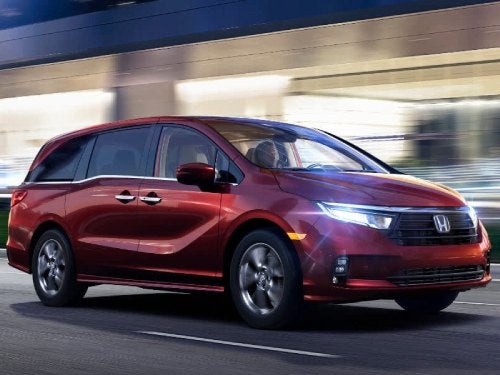 2024 Honda Odyssey driving down a road at night with headlights on
