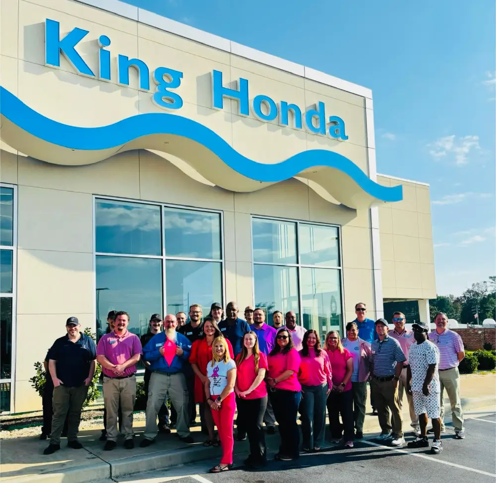 King Honda Car World team members standing outside the dealership wearing pink in support of breast cancer awareness